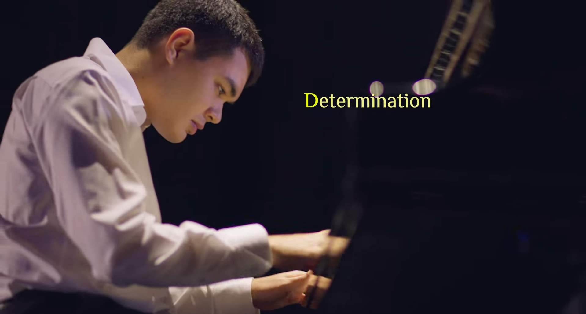 A pianist dressed in formal white shirt performing on stage, paired with the word “Determination”